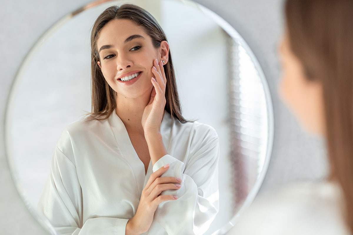 Brunette lady admiring her face in the mirror