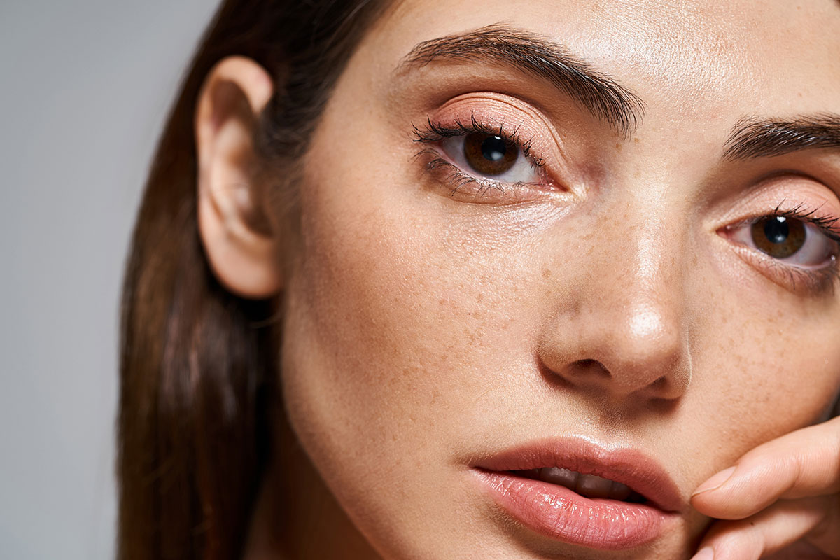 Brunette lady with some freckles on her face and pink lipstick