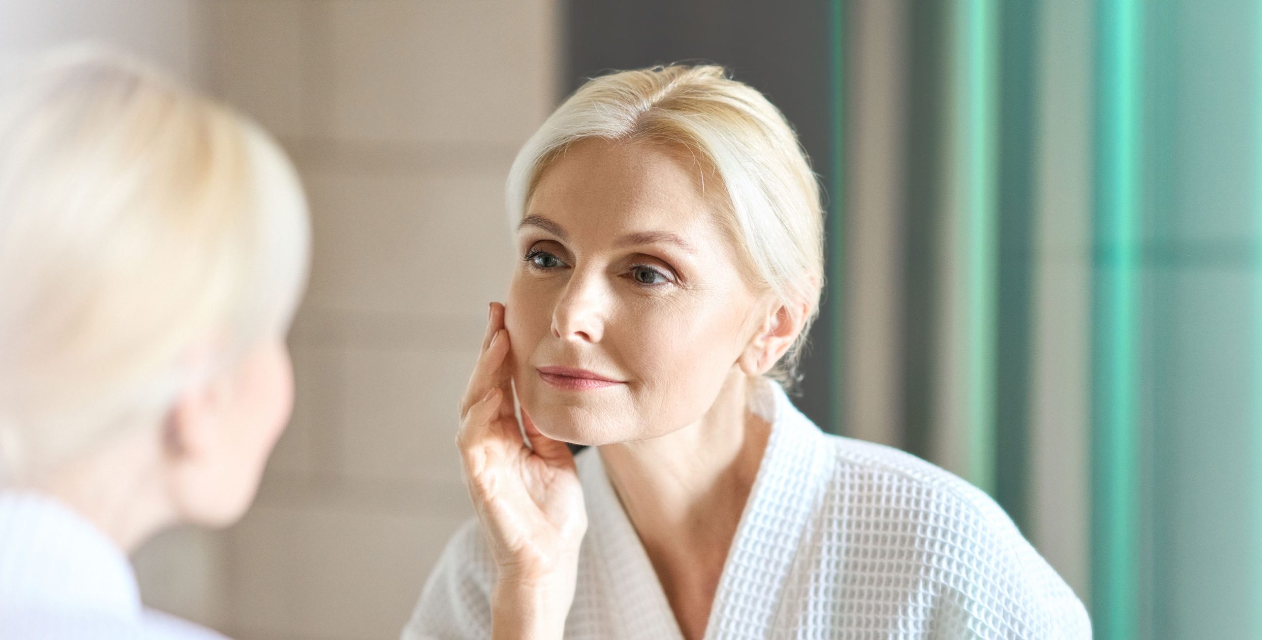 Blonde woman admiring her skin in the mirror