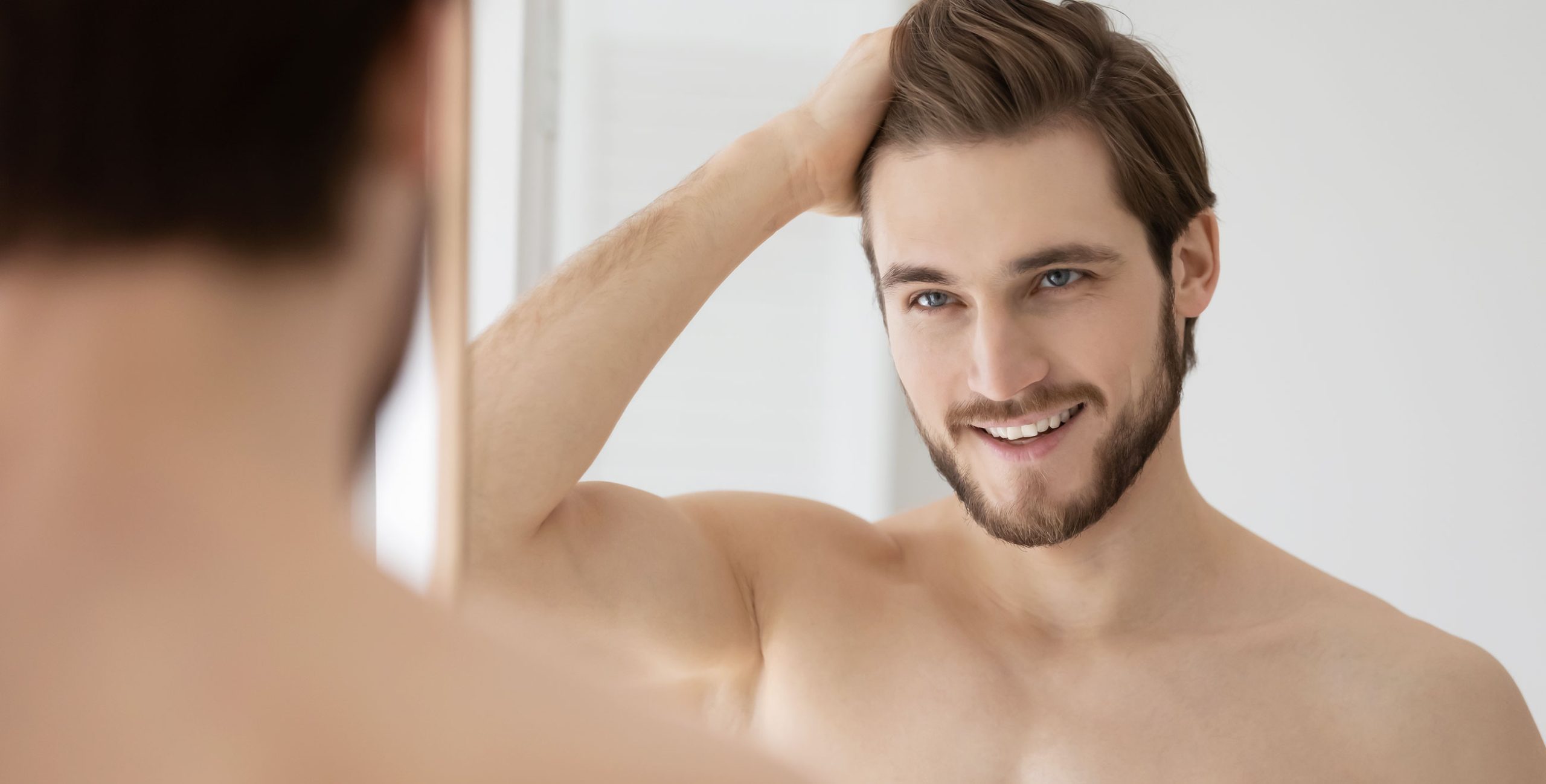 Young man admiring his features in the mirror