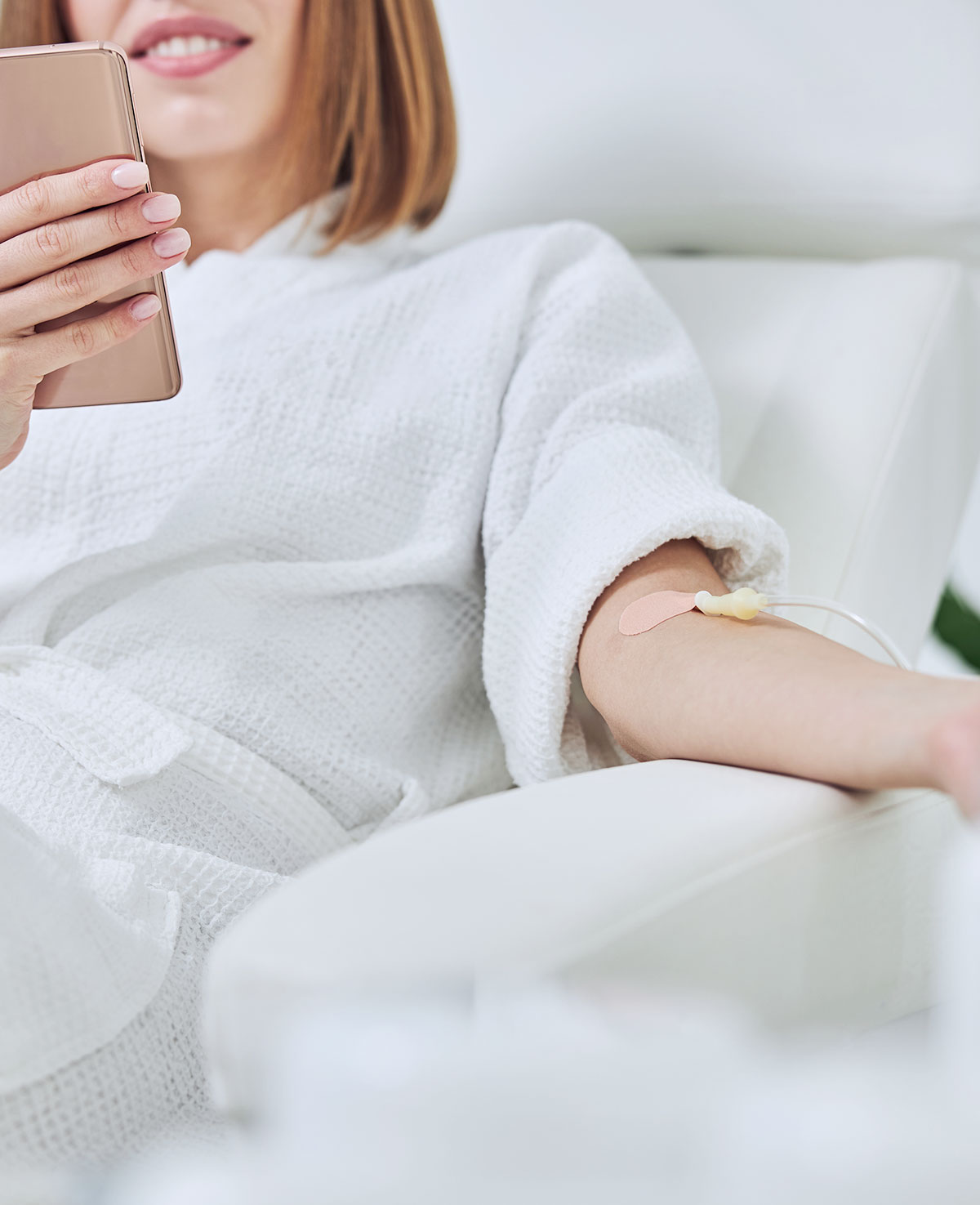 Ginger lady on her phone while getting IV Treatment